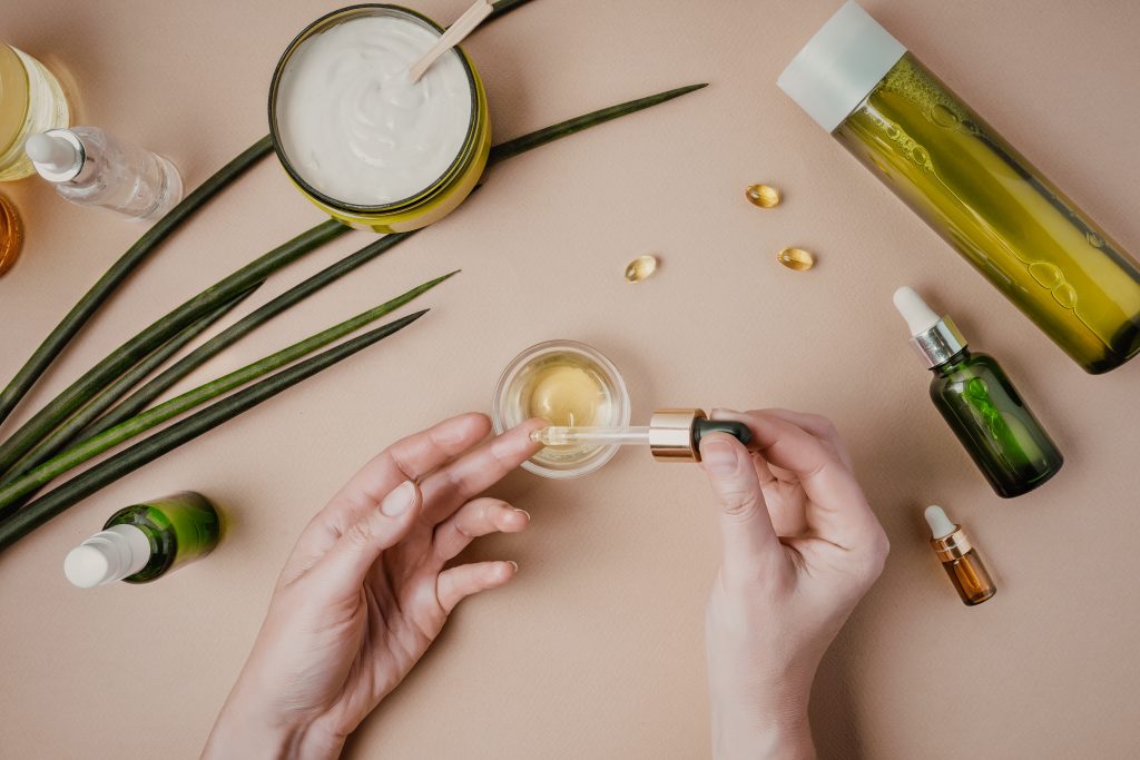 Woman cosmetologist cosmetics testing. Natural organic cosmetics. Serum hair mask. Flat lay pastel