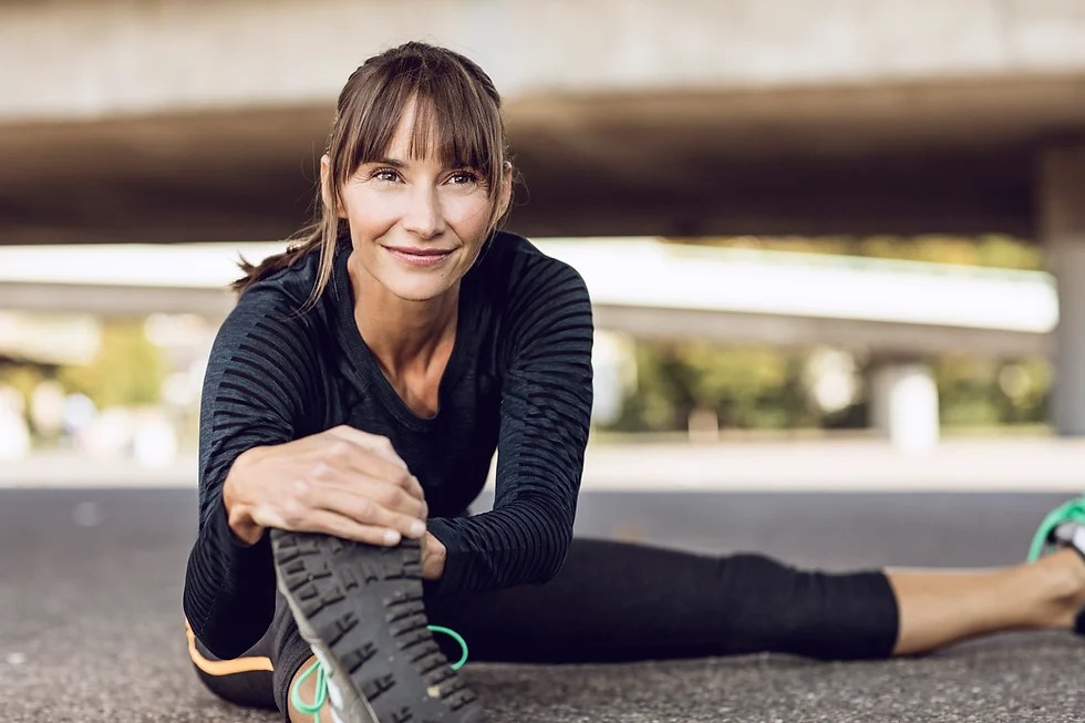 femme brune faisant du sport en étirant ses pieds avec sa main
