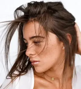 femme touchant des cheveux bruns avec sa main