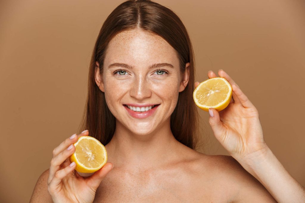 antioxydant_femme aux cheveux bruns, visage heureux, riant avec des citrons antioxydant dans sa main