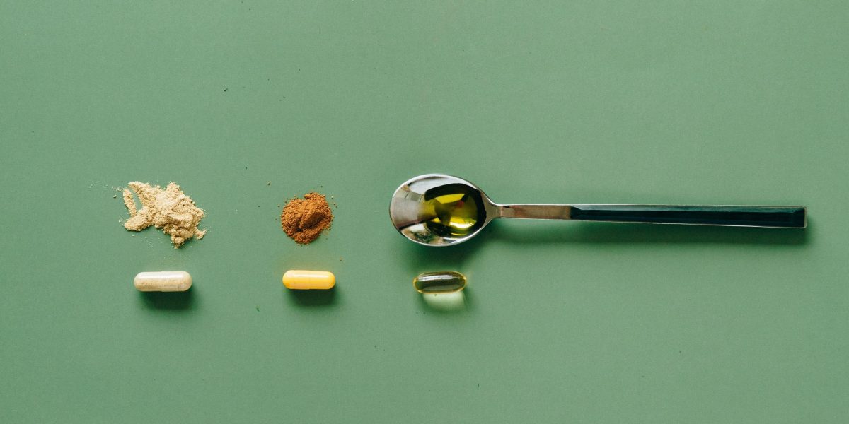 spoon powder and gelule food supplements on green background