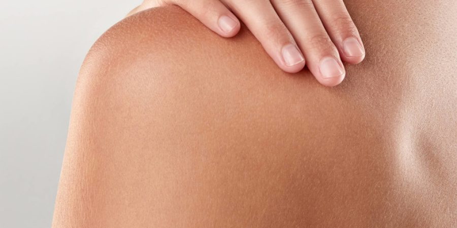 huid macro zoom van een meisje met haar hand op haar schouder