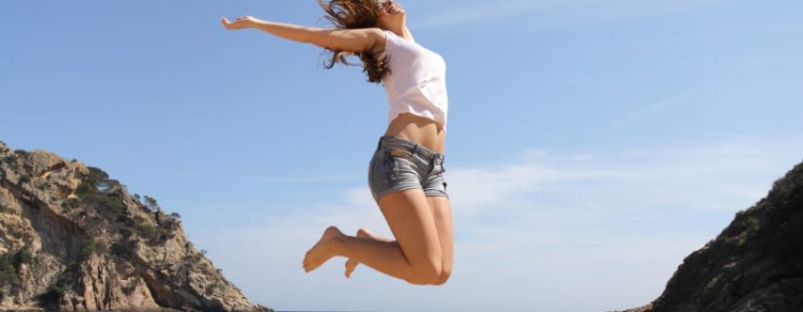 Frau springt glücklich am Strand